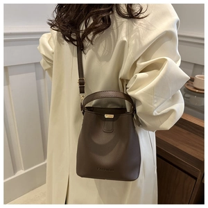 Detail view of brown matte leather bucket bag with FASHION logo and gold hardware details