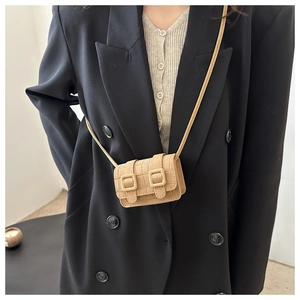 Detail of camel crocodile pattern mini crossbody bag with square buckles on black blazer