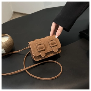 Detail of brown crocodile pattern small crossbody bag with dual buckle closure