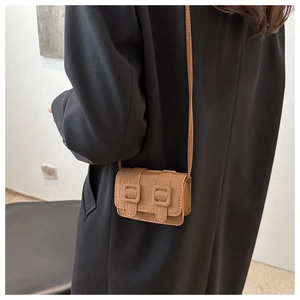 Detail of warm brown mini square crossbody bag with crocodile texture and buckles