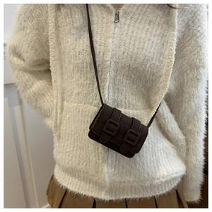 Detail of dark brown faux leather crossbody bag featuring crocodile texture and double buckles