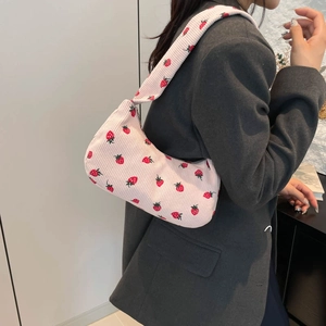 Sac croissant en velours côtelé rose avec broderies fraises porté à l'épaule