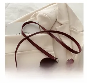 Detail view of burgundy suede bucket bag featuring slim leather straps and dual zipper design