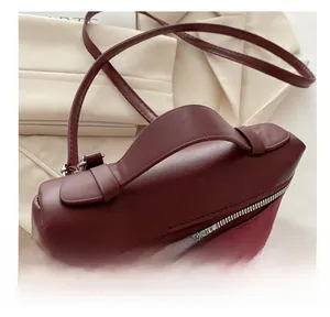 Detail of burgundy bucket bag featuring a smooth leather handle and zipper closure