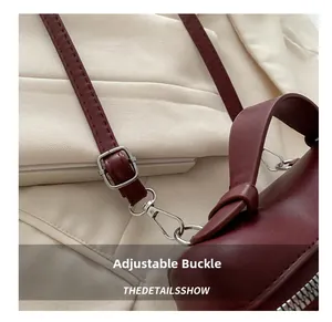 Detail of burgundy leather shoulder bag showing adjustable silver buckle and spring hook