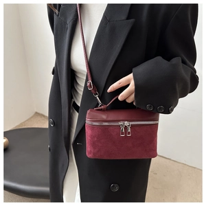 Detail of wine red bucket bag showing the mix of smooth faux leather and suede texture
