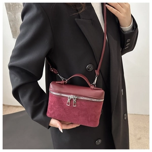 Detail of burgundy patchwork bucket bag featuring dual zippers and smooth leather texture