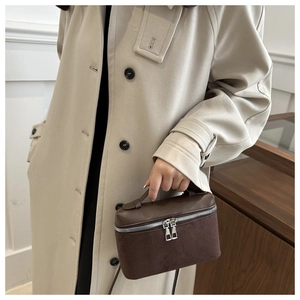 Detail of dark brown box-shaped handbag with double zippers and suede leather stitching