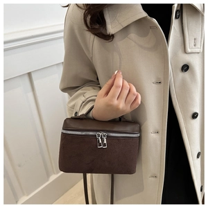 Detail of vintage brown suede and leather bucket bag showing dual zippers and texture