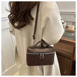Detail view of small brown crossbody bucket bag in matte leather and suede finish