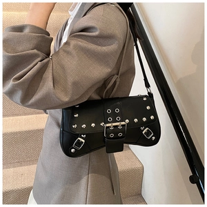 Vue détaillée du sac baguette punk noir avec clous et boucles porté par le modèle