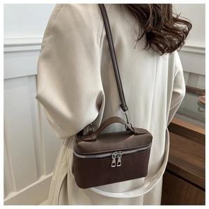 Detail of dual-texture brown bucket bag featuring smooth leather and suede stitching