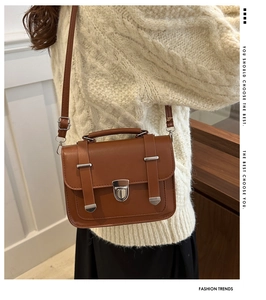 Brown leather retro satchel showing adjustable strap and top handle in a lifestyle setting