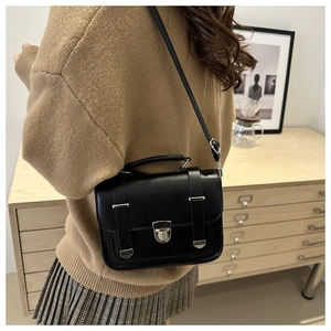 Dettaglio borsa a tracolla vintage nera con cinturino regolabile indossata su un maglione