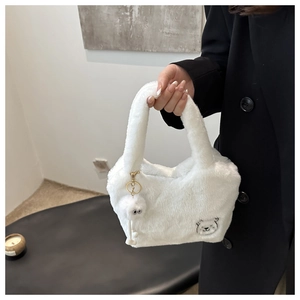 Détail d'un sac à main blanc en peluche avec broderie d'ours et pompon décoratif