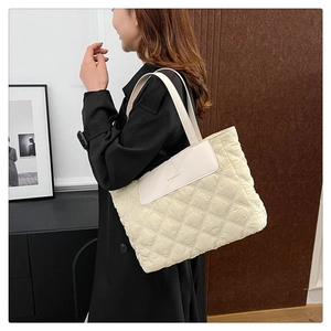 Detail of cream quilted tote bag featuring diamond stitching and FASHION leather patch