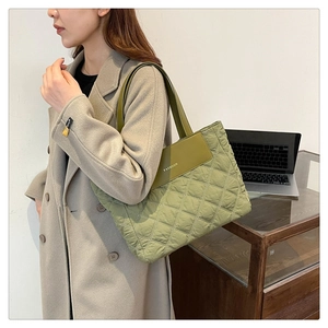 Olive green quilted tote bag with FASHION lettering shown in an office setting