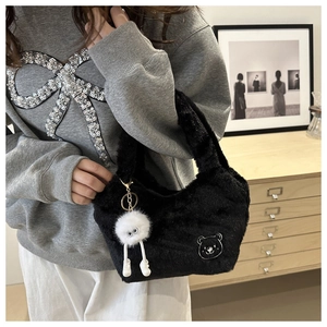 Détail d'un sac à main noir en fausse fourrure avec broderie ours et breloque monstre blanc