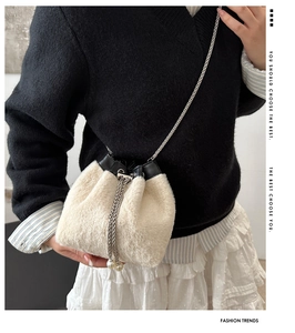 Gros plan du sac seau en fausse fourrure blanche avec cordon perlé et bandoulière chaîne