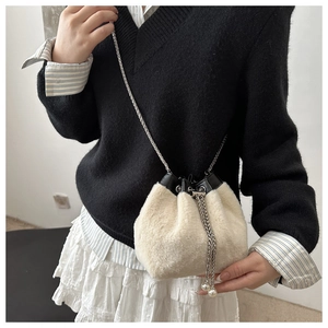 Détail du sac seau en fausse fourrure beige avec chaîne argentée et breloques en perles