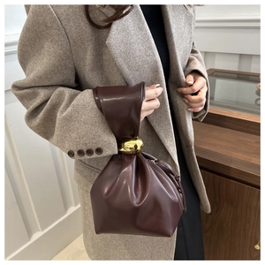 Close-up of dark brown leather bucket bag with unique gold metallic hardware detail