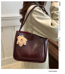 Détail d'un sac cabas rouge foncé avec coutures incurvées et charm en peluche étoile