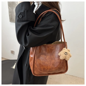 Détail du sac cabas marron vintage en cuir texturé avec pendentif étoile en peluche