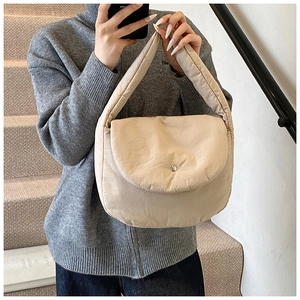 Detail view of beige quilted puffy shoulder bag with silver round metal snap closure