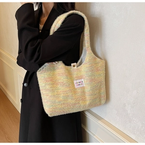 Detail der bunten Plüsch-Stricktasche mit weicher Textur und Etikett auf schwarzem Mantel