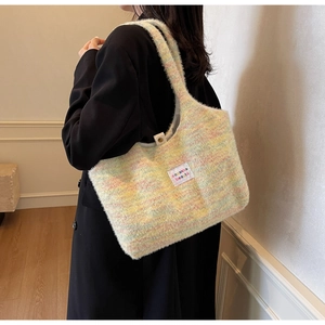 Detail der bunten Plüsch-Stricktasche mit Markenlabel auf weicher Macaron-Garntextur