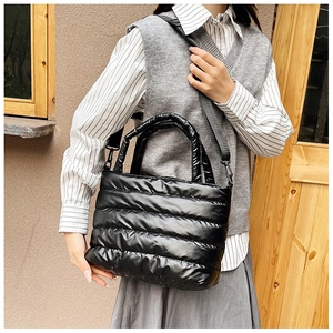 Detail of black quilted down tote bag with padded handles and shiny satin texture finish