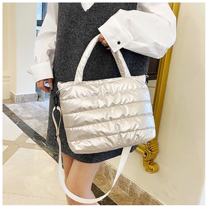 Detail of champagne quilted down tote bag with dual handles and adjustable shoulder strap