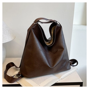 Detail of dark brown leather tote bag texture and textile strap on a white table
