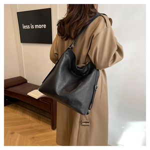Detail view of large black tote bag featuring textured matte leather and adjustable strap