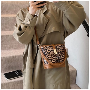 Detail of leopard print bucket bag featuring brown leather trim and golden metal clasp