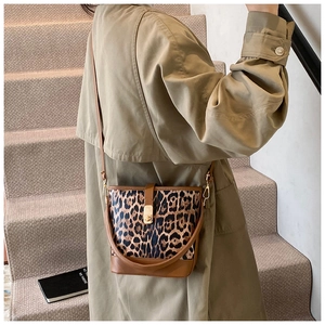 Détail du sac seau léopard avec boucle en métal doré et bandoulière en cuir brun