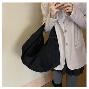 Lifestyle view of a large black suede tote bag styled with a minimalist chic outfit