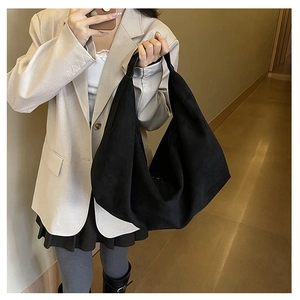 Minimalist black suede tote bag shown on shoulder with spacious hobo silhouette design
