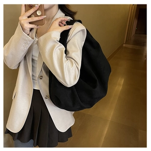 Fashionable black oversized half-moon shoulder bag styled with a beige blazer suit