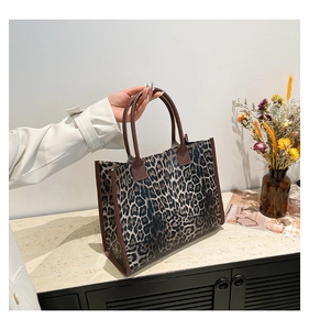 Detail shot of leopard print tote bag with brown trim on a minimalist counter