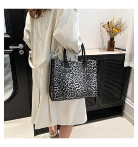 Detailed view of large leopard print tote bag with black handles in a lifestyle setting