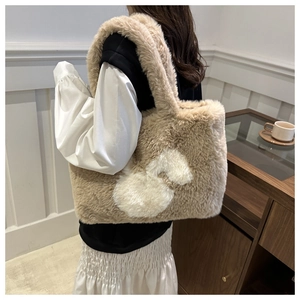Close-up of fluffy khaki shoulder bag with white heart detail on soft faux rabbit fur