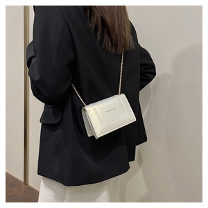 Rear view of a model wearing the pearl white small square bag with a gold chain strap