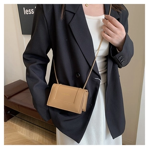 Detail view of khaki square crossbody bag with gold chain strap on black blazer outfit