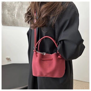 Detail einer roten Plissee-Beuteltasche mit matter Wildlederoptik und runden Griffen