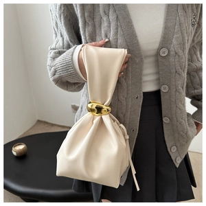 Detail of cream drawstring bucket bag with a large gold metal ring handle