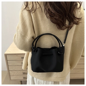 Minimalistische schwarze Plissee-Beuteltasche mit Ringgriff, am Modell präsentiert