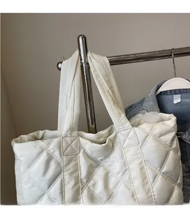 Dettaglio della borsa shopper trapuntata bianca con manici spessi ed etichetta alla moda