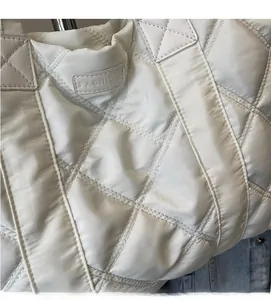 Dettaglio della borsa tote trapuntata bianca con texture morbida e etichetta Fashion