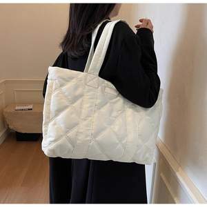 Dettaglio borsa tote bianca trapuntata con etichetta fashion e tracolla imbottita